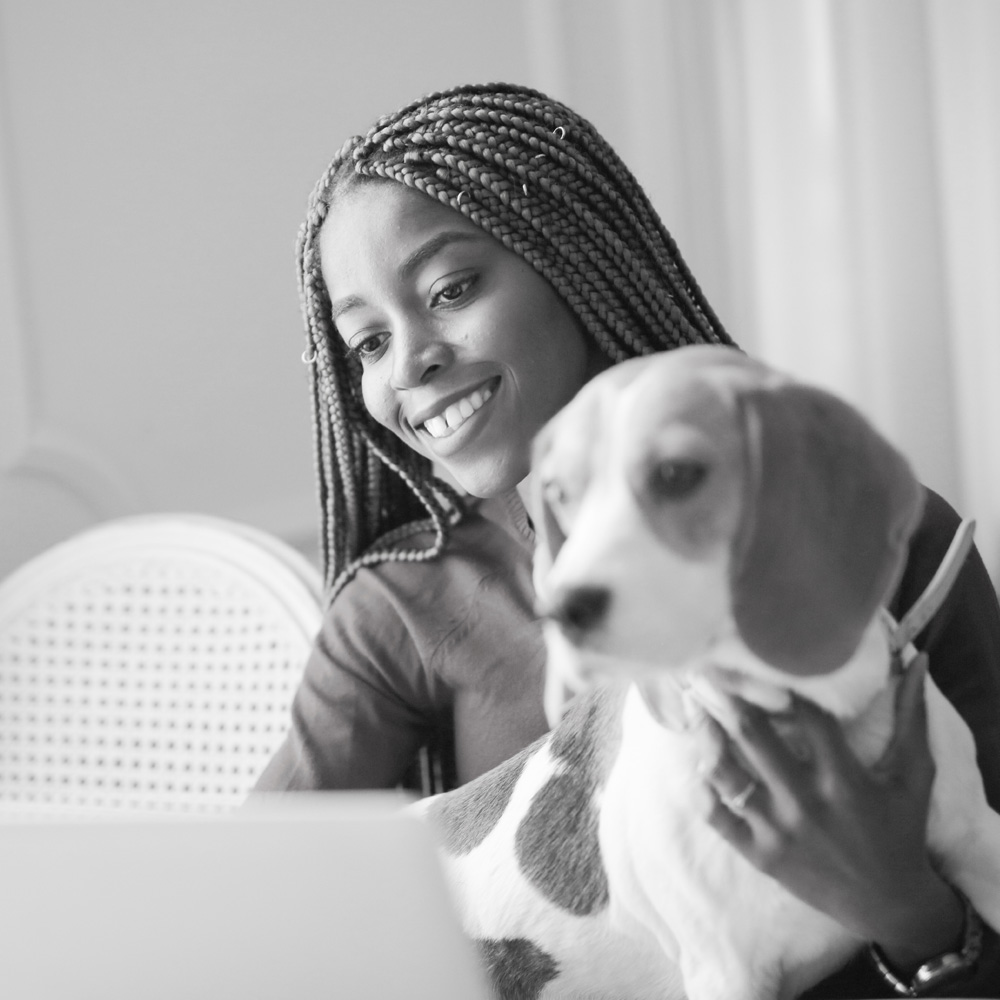 Woman holding her dog while using her computer.